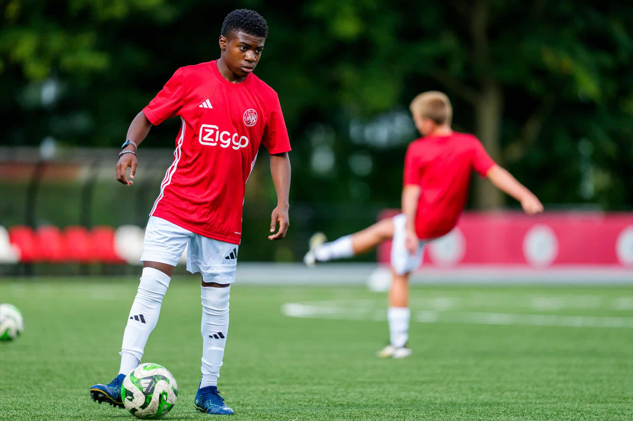 Energieke jeugdvoetballers in Ajax-shirt vieren overwinning op het veld.