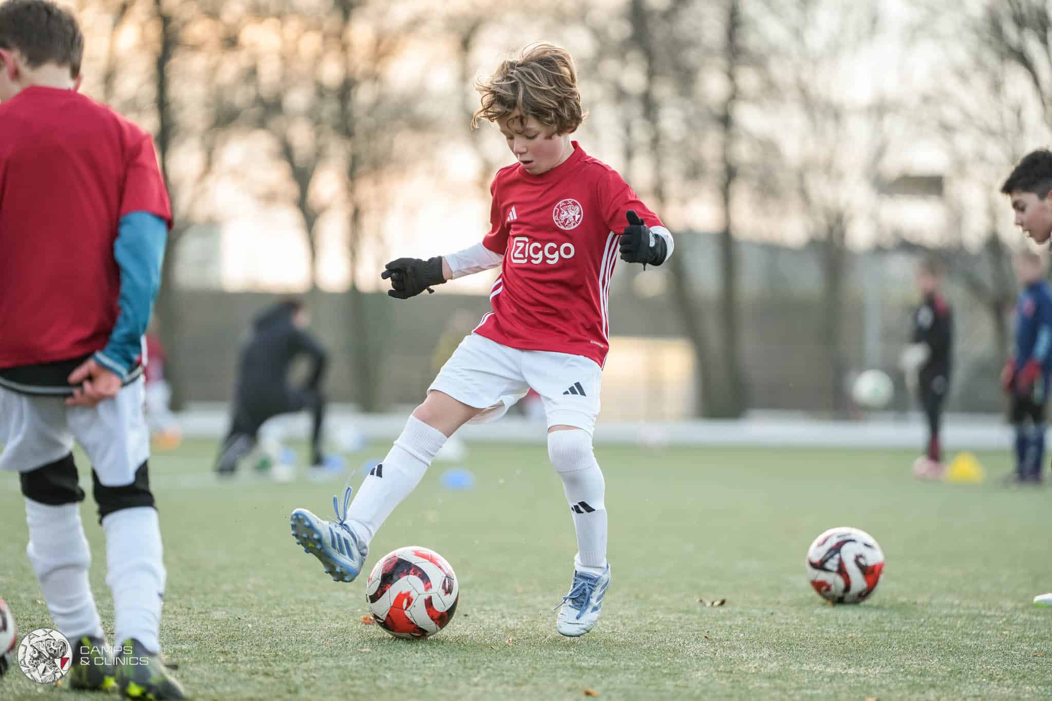 Energieke jeugdvoetballers in Ajax-shirt vieren overwinning op het veld.
